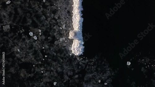 Aerial Top Lockdown Shot Of Petoskey Pierhead Lighthouse On Frozen Lake - Marquette, Michigan photo