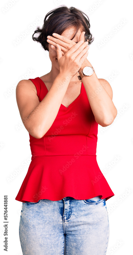 Beautiful young woman with short hair wearing casual style with sleeveless shirt covering eyes and mouth with hands, surprised and shocked. hiding emotion Beautiful young woman with short hair wearing casual style with sleeveless shirt covering eyes and mouth with hands, surprised and shocked. hiding emotion