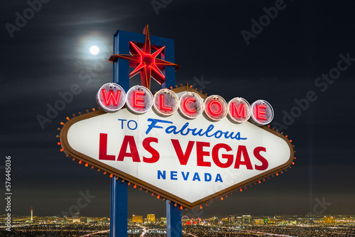 Night view of the famous Welcome to Fabulous Las Vegas sign with cityscape skyline in background.