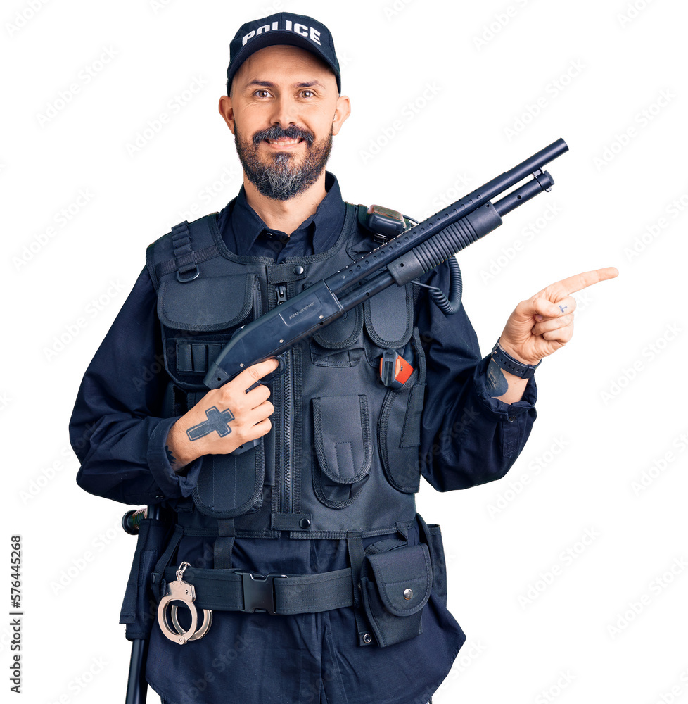 Young handsome man wearing police uniform holding shotgun smiling happy pointing with hand and finger to the side Young handsome man wearing police uniform holding shotgun smiling happy pointing with hand and finger to the side