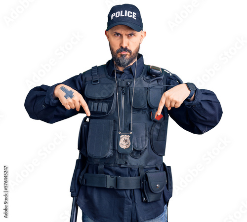 Young handsome man wearing police uniform pointing down looking sad and upset, indicating direction with fingers, unhappy and depressed.