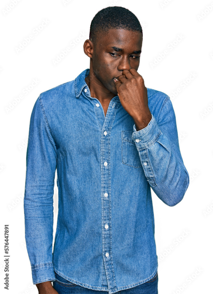 Young african american man wearing casual clothes looking stressed and nervous with hands on mouth biting nails. anxiety problem. Young african american man wearing casual clothes looking stressed and nervous with hands on mouth biting nails. anxiety problem.