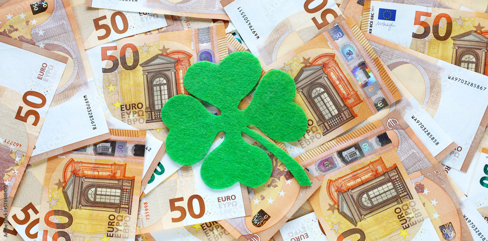 Banner with green felt four leaf clover on 50 fifty euro banknotes background. Euro currency in Europe. Financial, bank, business. Lucky talisman. Saint Patrick's day. Place for text.