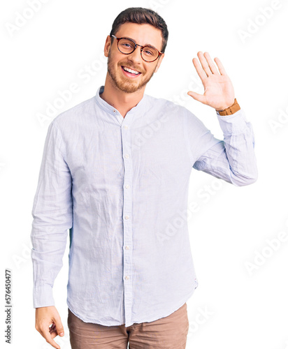 Handsome young man with bear wearing elegant business shirt and glasses waiving saying hello happy and smiling, friendly welcome gesture