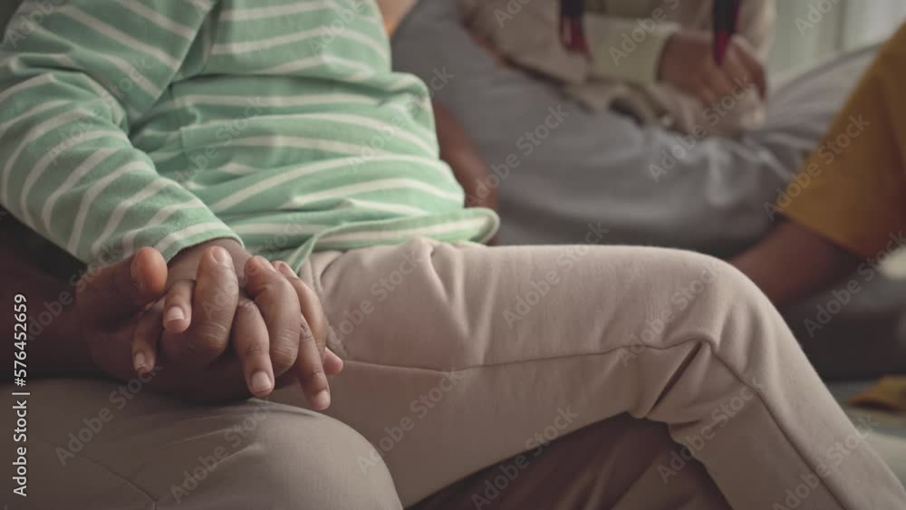 Closeup of unrecognizable Black man holding hand of his little daughter sitting on his laps while playing boardgame at home together Closeup of unrecognizable Black man holding hand of his little daughter sitting on his laps while playing boardgame at home together