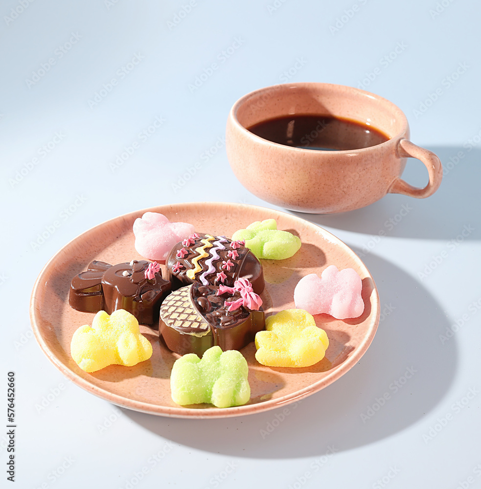 A Pink Cup of Coffee, A Festive Saucer of Pink and Yellow Easter Bunny Chocolate Bon Bons and Pastel Gummy Candies A Pink Cup of Coffee, A Festive Saucer of Pink and Yellow Easter Bunny Chocolate Bon Bons and Pastel Gummy Candies