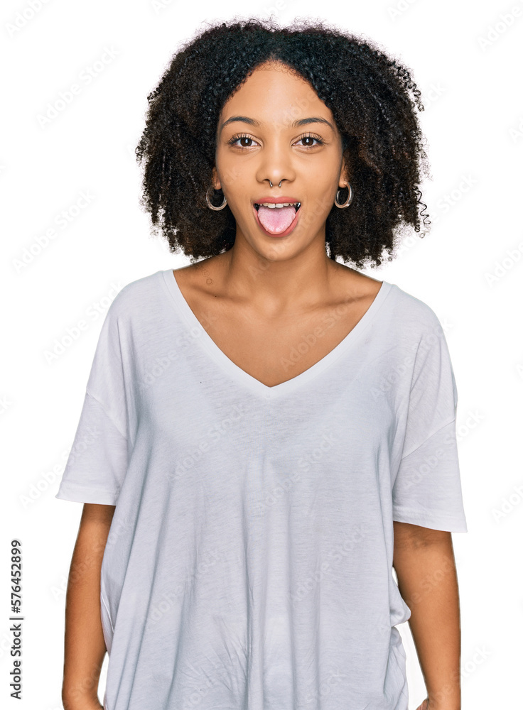 Young african american girl wearing casual clothes sticking tongue out happy with funny expression. emotion concept. Young african american girl wearing casual clothes sticking tongue out happy with funny expression. emotion concept.