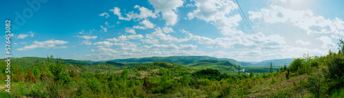 Panorama of the spring forest near the mountain town. Picturesque landscape of a sunny day.