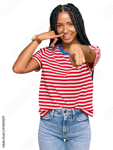 Beautiful hispanic woman wearing casual clothes smiling doing talking on the telephone gesture and pointing to you. call me.