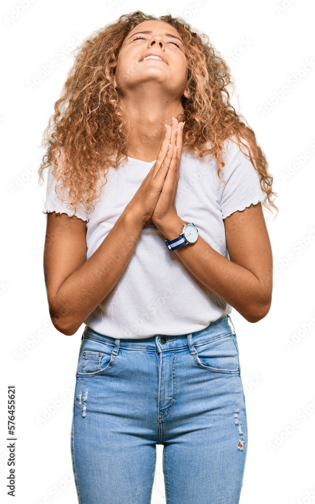 Beautiful caucasian teenager girl wearing casual white tshirt begging and praying with hands together with hope expression on face very emotional and worried. begging. Beautiful caucasian teenager girl wearing casual white tshirt begging and praying with hands together with hope expression on face very emotional and worried. begging.