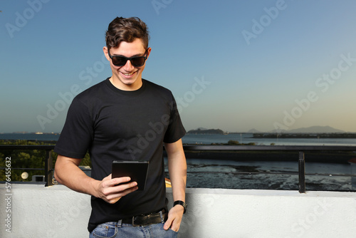 Foto Joven mirando su Tablet mientras disfruta del verano al aire libre mientras cae la puesta de sol