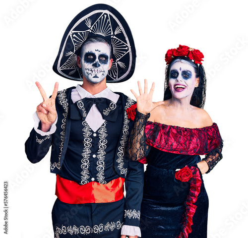 Young couple wearing mexican day of the dead costume over background showing and pointing up with fingers number seven while smiling confident and happy.