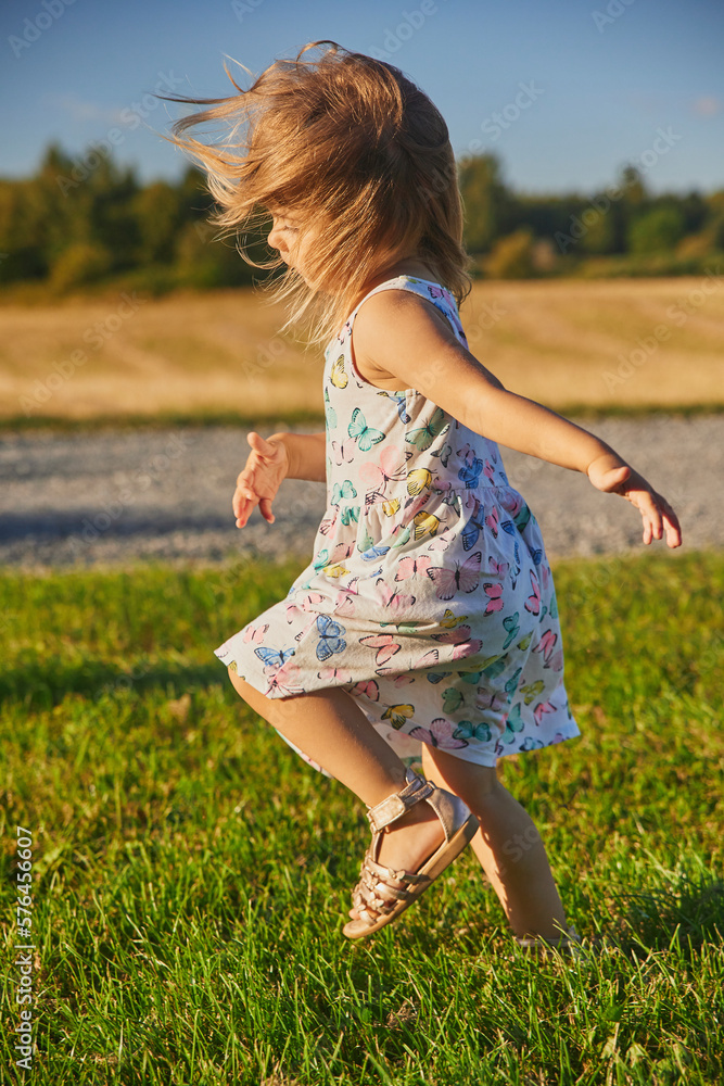 charming child in a sundress running down the street in the suburbs charming child in a sundress running down the street in the suburbs