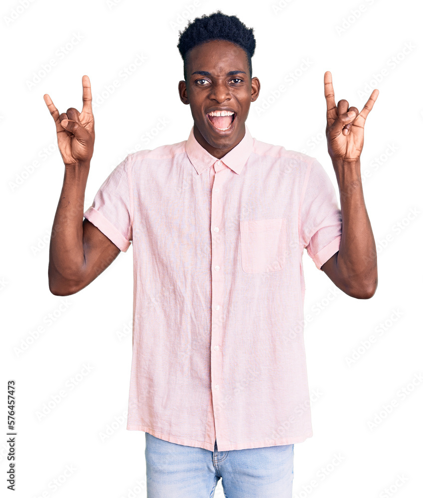 Young african american man wearing casual clothes shouting with crazy expression doing rock symbol with hands up. music star. heavy concept. Young african american man wearing casual clothes shouting with crazy expression doing rock symbol with hands up. music star. heavy concept.
