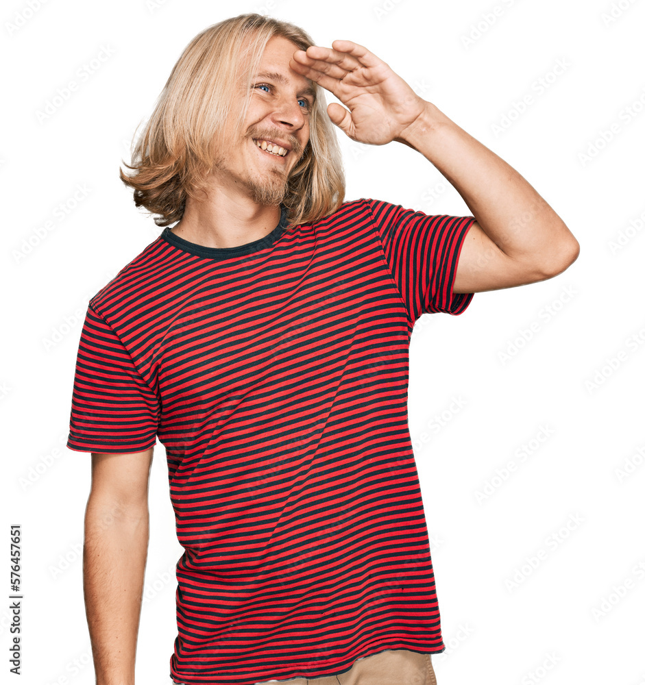 Caucasian man with blond long hair wearing casual striped t shirt very happy and smiling looking far away with hand over head. searching concept. Caucasian man with blond long hair wearing casual striped t shirt very happy and smiling looking far away with hand over head. searching concept.