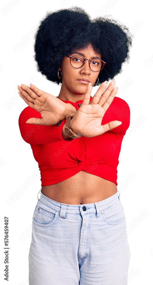 Young african american girl wearing casual clothes and glasses rejection expression crossing arms and palms doing negative sign, angry face Young african american girl wearing casual clothes and glasses rejection expression crossing arms and palms doing negative sign, angry face