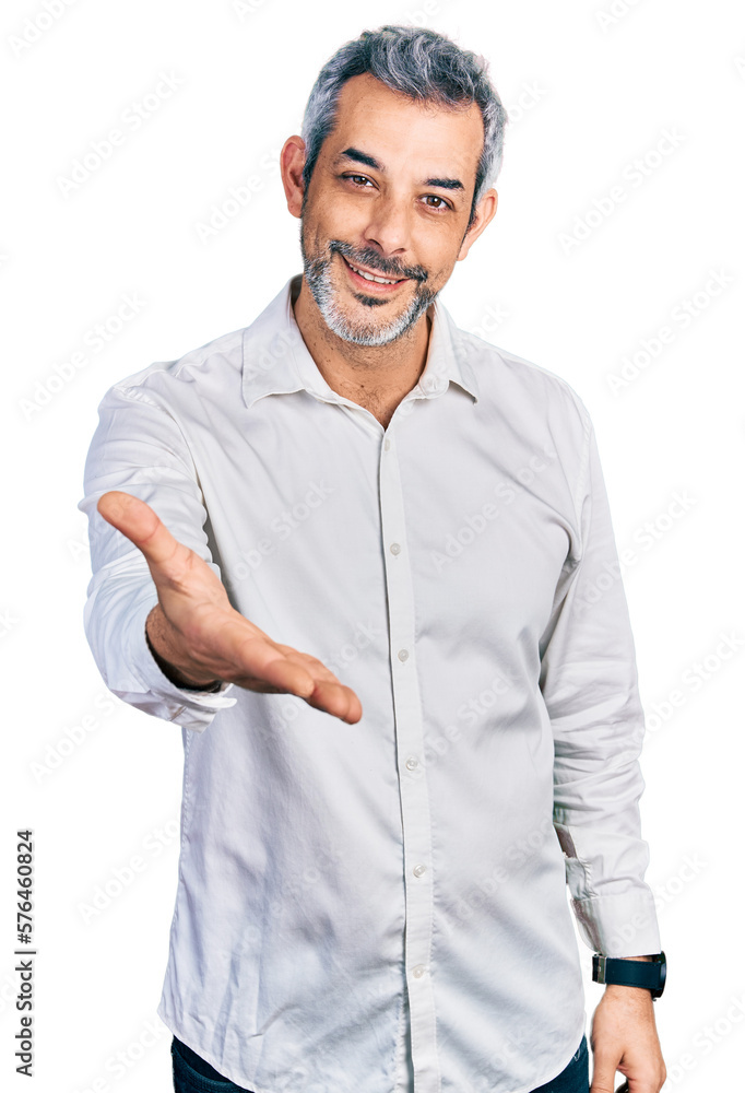 Middle age hispanic with grey hair wearing casual white shirt smiling cheerful offering palm hand giving assistance and acceptance. Middle age hispanic with grey hair wearing casual white shirt smiling cheerful offering palm hand giving assistance and acceptance.