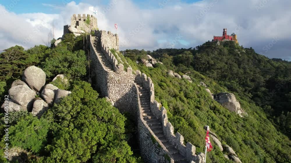 Aerial view of the town of Sintra in Portugal, historical Castelo Dos Mouros (moors castle) fortress, walls and Pena Palace in the summer, taken with a drone, on a beautiful green summit rocky hilltop