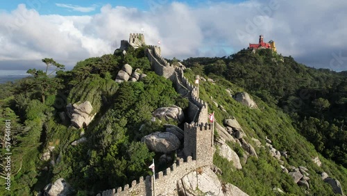 Aerial view of the town of Sintra in Portugal, historical Castelo Dos Mouros (moors castle) fortress, walls and Pena Palace in the summer, taken with a drone, on a beautiful green summit rocky hilltop photo