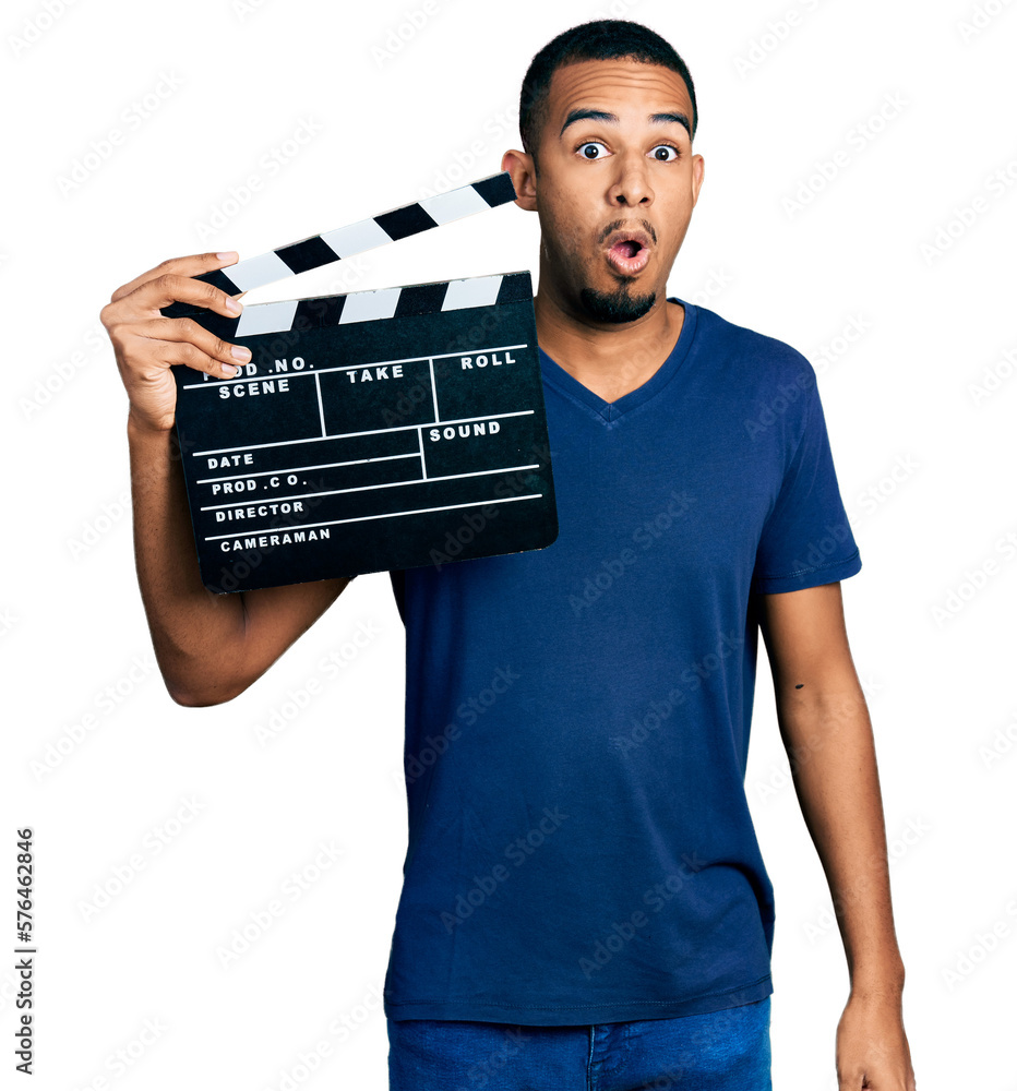 Young african american man holding video film clapboard scared and amazed with open mouth for surprise, disbelief face Young african american man holding video film clapboard scared and amazed with open mouth for surprise, disbelief face