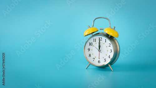 Retro silver alarm clock.  12:00, am, pm. Blue background.