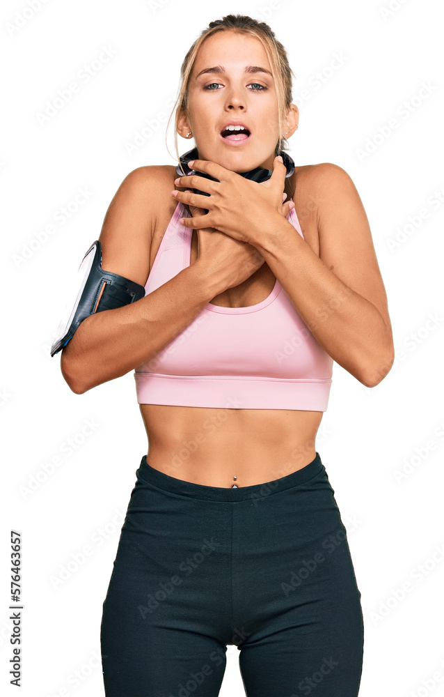 Young blonde woman wearing gym clothes and using headphones shouting and suffocate because painful strangle. health problem. asphyxiate and suicide concept. Young blonde woman wearing gym clothes and using headphones shouting and suffocate because painful strangle. health problem. asphyxiate and suicide concept.
