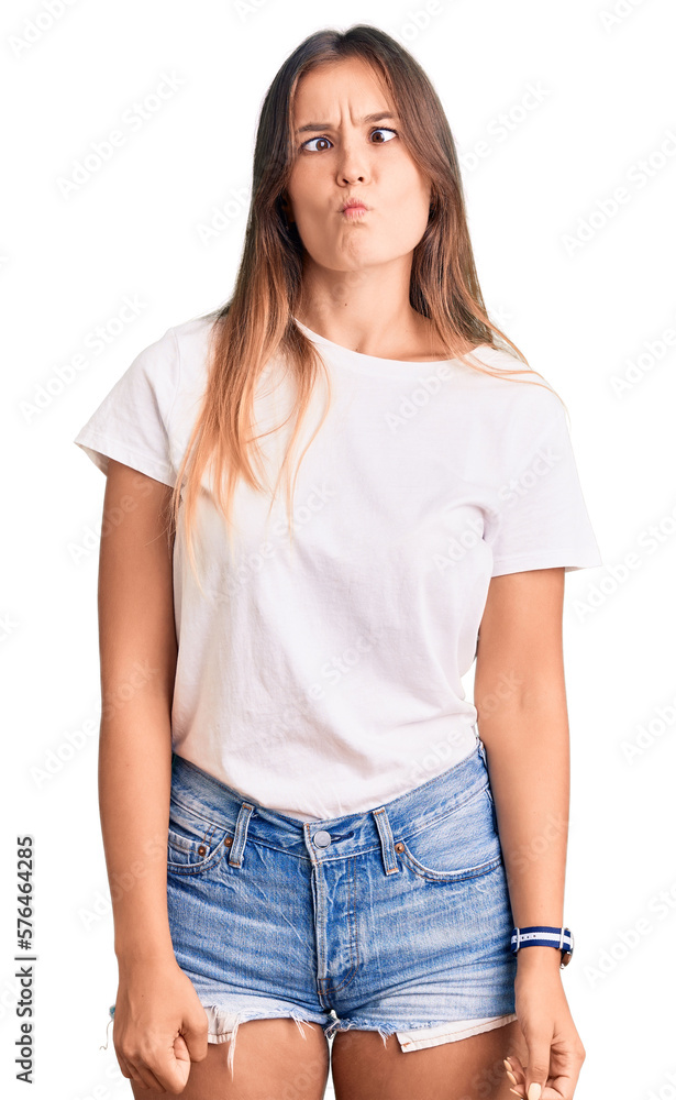 Beautiful caucasian woman wearing casual white tshirt making fish face with lips, crazy and comical gesture. funny expression. Beautiful caucasian woman wearing casual white tshirt making fish face with lips, crazy and comical gesture. funny expression.