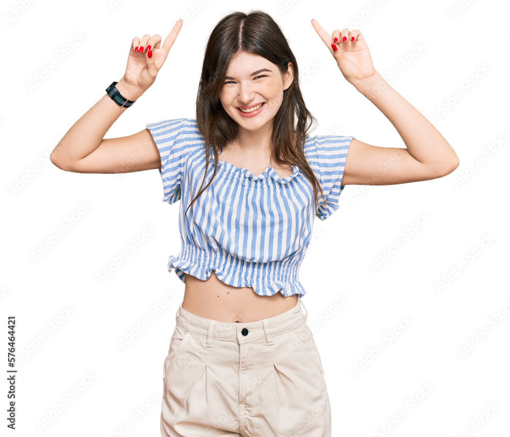 Young beautiful caucasian girl wearing casual clothes smiling amazed and surprised and pointing up with fingers and raised arms. Young beautiful caucasian girl wearing casual clothes smiling amazed and surprised and pointing up with fingers and raised arms.