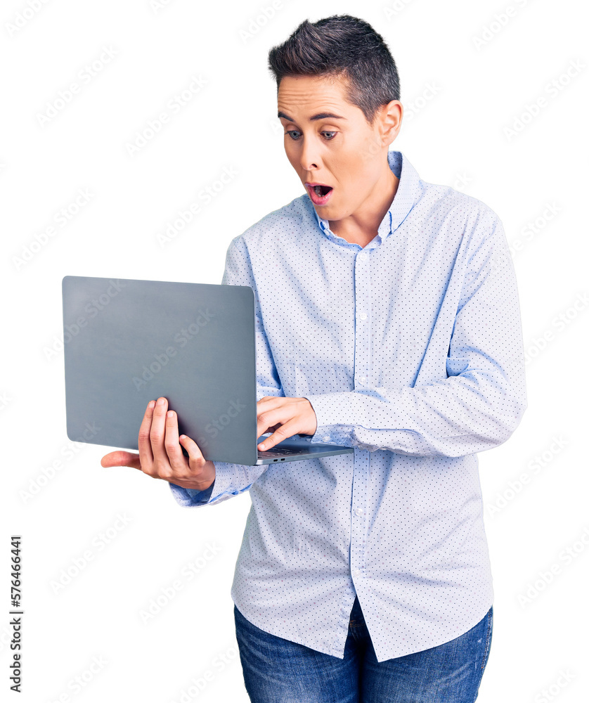 Young woman with short hair holding laptop scared and amazed with open mouth for surprise, disbelief face Young woman with short hair holding laptop scared and amazed with open mouth for surprise, disbelief face