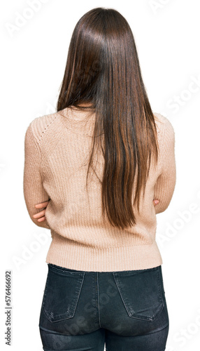 Young brunette woman wearing casual winter sweater standing backwards looking away with crossed arms