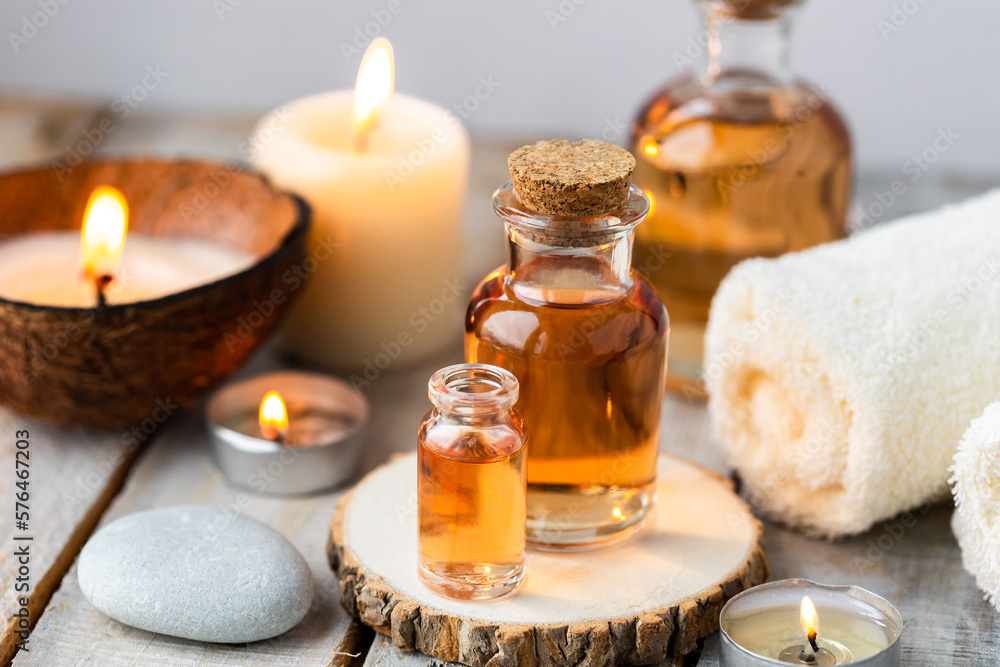 Concept of spa treatment in salon with pure organic natural oil. Atmosphere of relax, detention. Aromatherapy, candles, towel, wooden background. Skin care, body gentle treatment - obrazy, fototapety, plakaty 