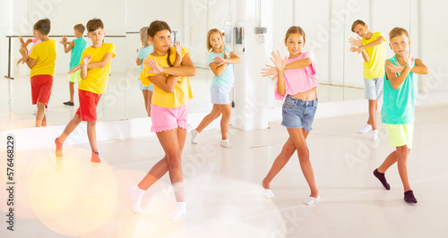 Group of kids training modern dance moves together in studio.