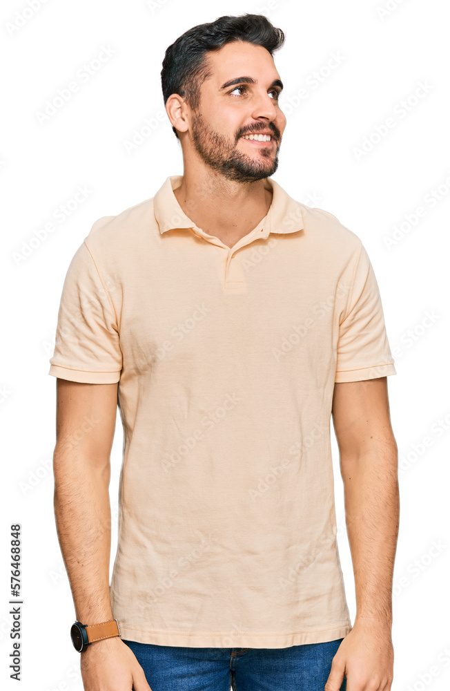 Young hispanic man wearing casual clothes looking away to side with smile on face, natural expression. laughing confident. Young hispanic man wearing casual clothes looking away to side with smile on face, natural expression. laughing confident.