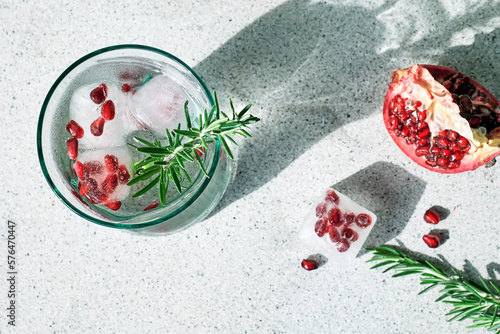 Pomegranate gin fizz cocktail with sparkling wine, rosemary and ice. Holidays refreshing alcoholic drink. Pomegranate cold detox beverage. photo