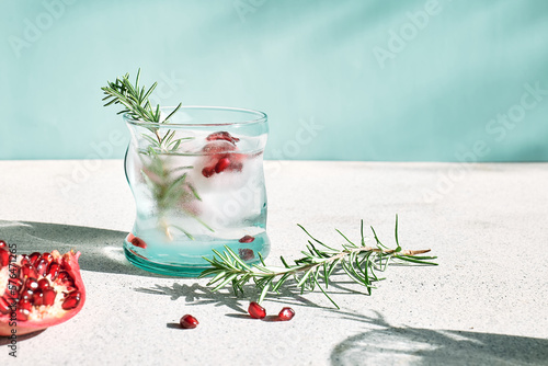 Pomegranate gin fizz cocktail with sparkling wine, rosemary and ice. Holidays refreshing alcoholic drink. Pomegranate cold detox beverage.
