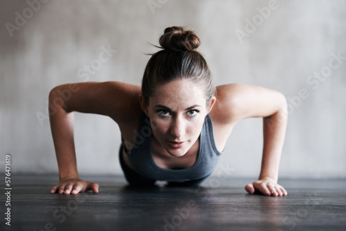 Its tough, but its worth it. Shot of a woman doing pushups at the gym.