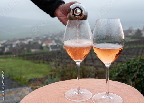 Fototapeta Naklejka Na Ścianę i Meble -  Tasting of premier cru sparkling rose wine with bubbles champagne outdoor with view on hilly pinot meunier vineyards in Hautvillers in February, near Epernay, France.