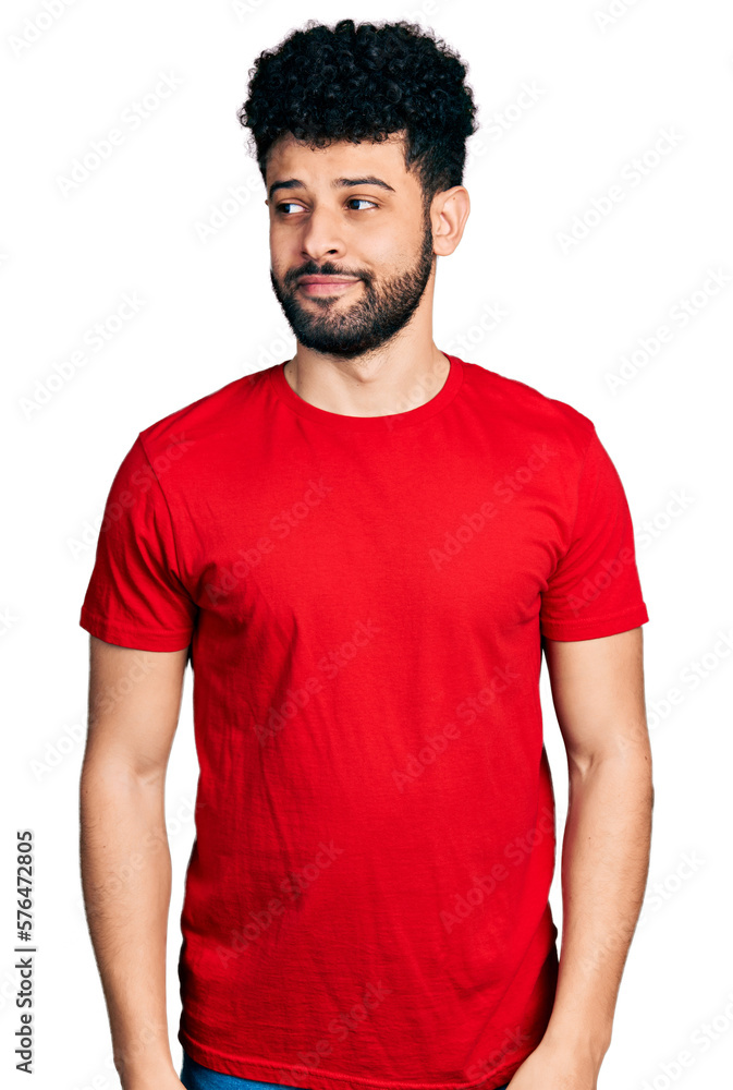 Young arab man with beard wearing casual red t shirt smiling looking to the side and staring away thinking. Young arab man with beard wearing casual red t shirt smiling looking to the side and staring away thinking.