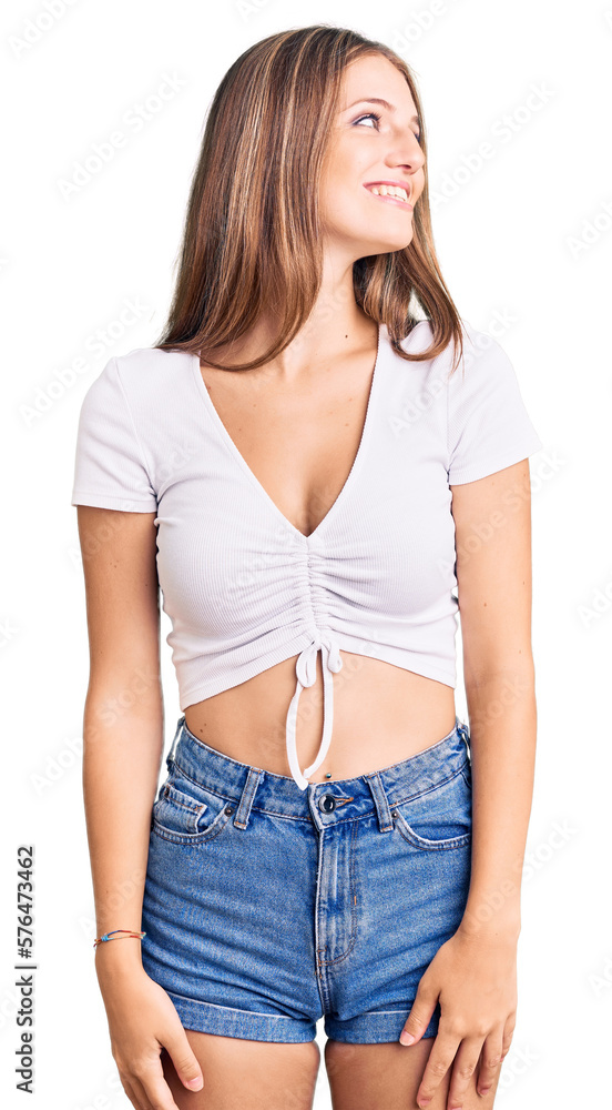 Young beautiful blonde woman wearing casual white tshirt looking away to side with smile on face, natural expression. laughing confident. Young beautiful blonde woman wearing casual white tshirt looking away to side with smile on face, natural expression. laughing confident.