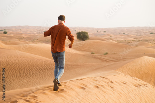 Man walking dunes at sunrise