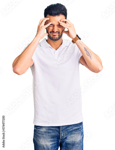 Young handsome hispanic man wearing casual clothes suffering from headache desperate and stressed because pain and migraine. hands on head.