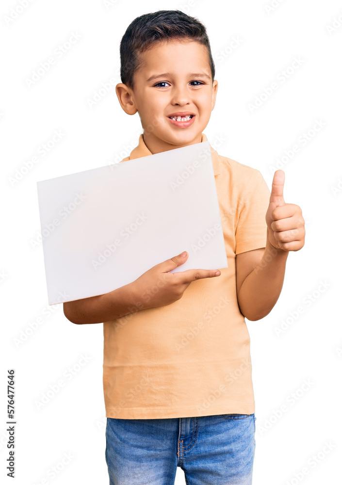 Little cute boy kid holding cardboard banner with blank space smiling happy and positive, thumb up doing excellent and approval sign Little cute boy kid holding cardboard banner with blank space smiling happy and positive, thumb up doing excellent and approval sign