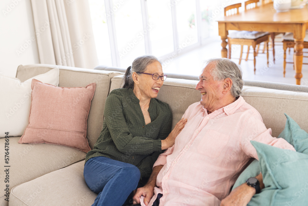 Happy senior diverse couple sitting on sofa and smiling Happy senior diverse couple sitting on sofa and smiling