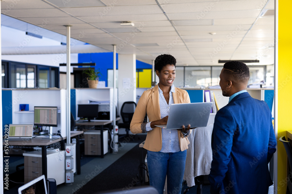 Diverse business people using laptop and discussing work at office