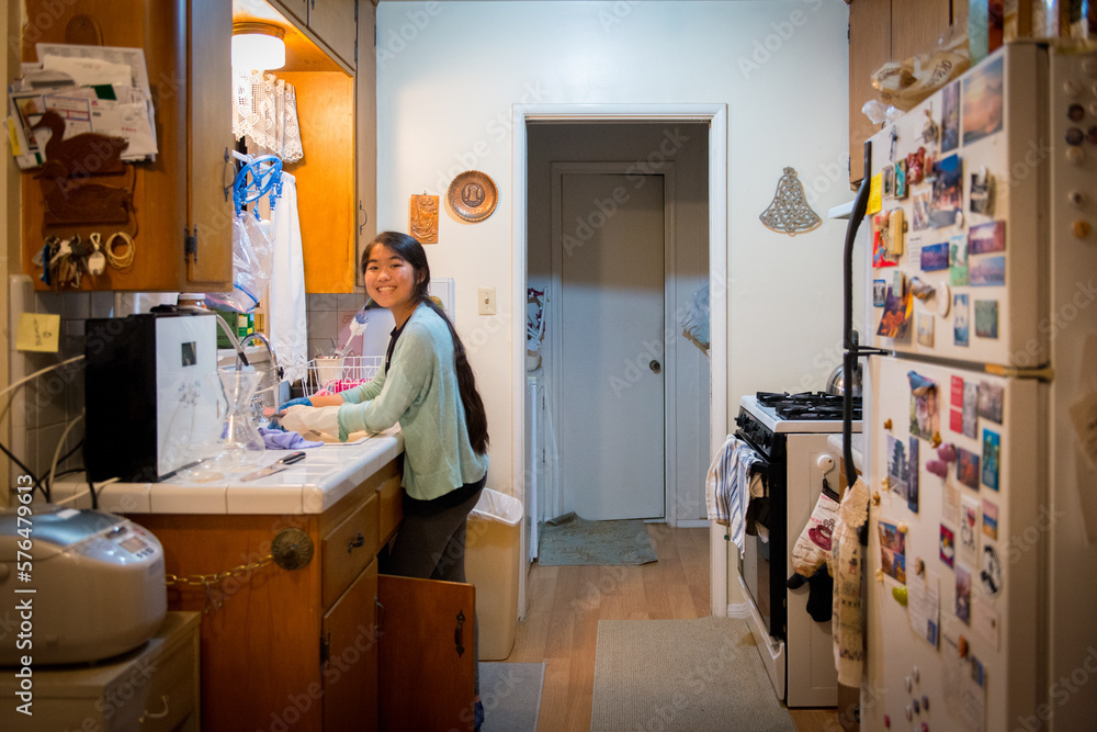 Obraz premium Young asian girl washing dishes after dinner