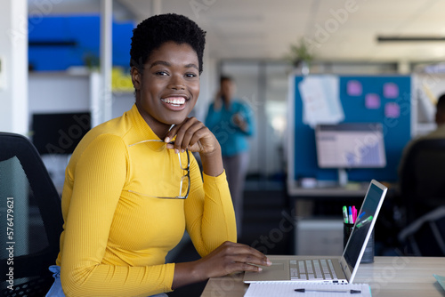 Portrait of african american businesswoman using laptop and smiling at office