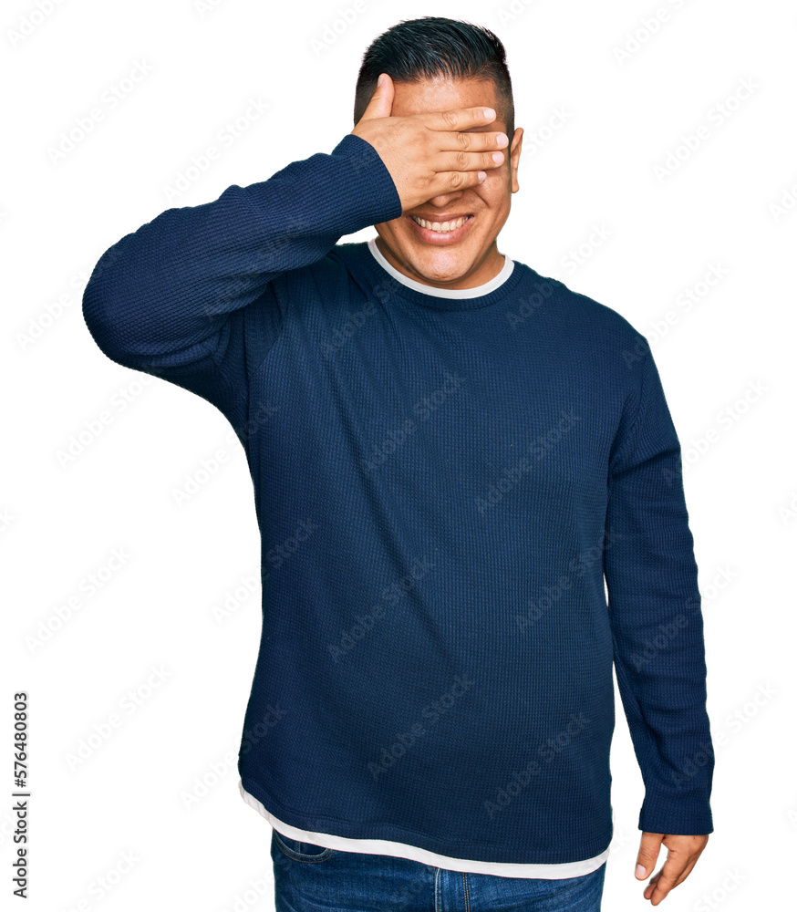 Young latin man wearing casual clothes smiling and laughing with hand on face covering eyes for surprise. blind concept. Young latin man wearing casual clothes smiling and laughing with hand on face covering eyes for surprise. blind concept.