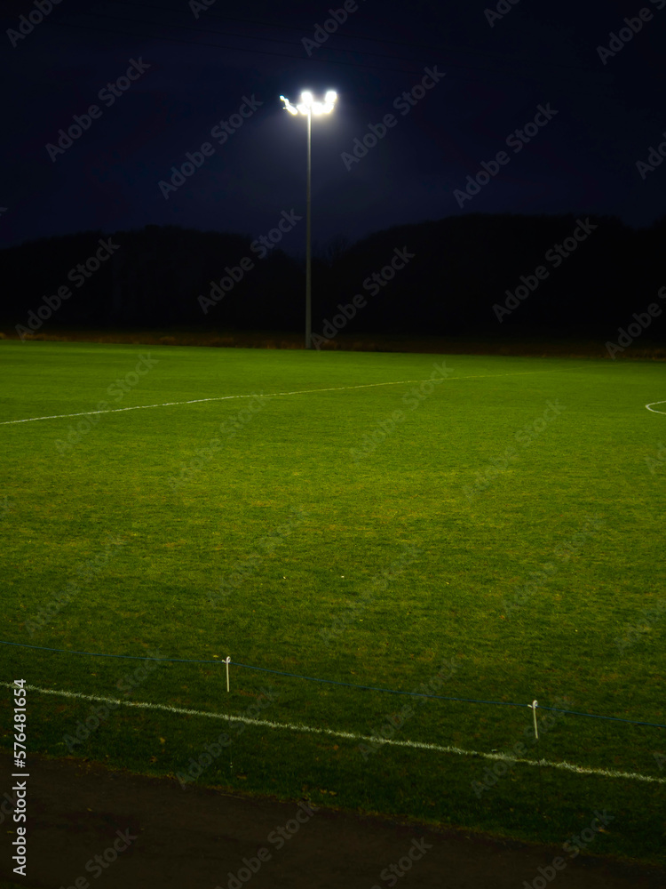 Obraz premium Training ground with grass illuminated by modern powerful LED lights. Efficient modern technology. Nobody.