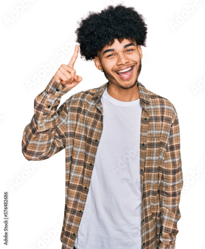 Young african american man with afro hair wearing casual clothes pointing finger up with successful idea. exited and happy. number one.