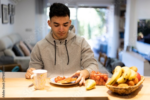 Hombre joven tomando el desayuno saludable en su casa por la mañana.